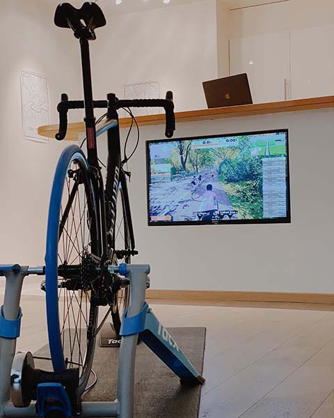 bike trainer set up facing a tv screen and laptop